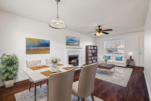 dining area with ceiling fan, dark wood-type flooring, and a high end fireplace