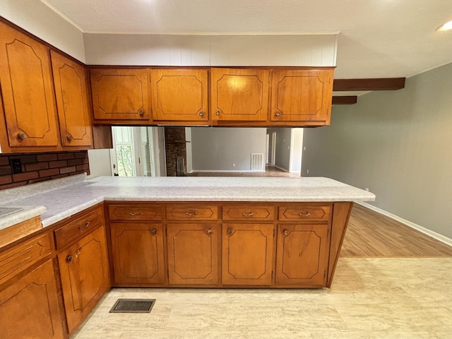 kitchen with kitchen peninsula, light wood-type flooring, and tasteful backsplash