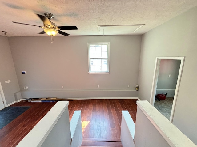 unfurnished room with ceiling fan, a textured ceiling, and dark wood-type flooring