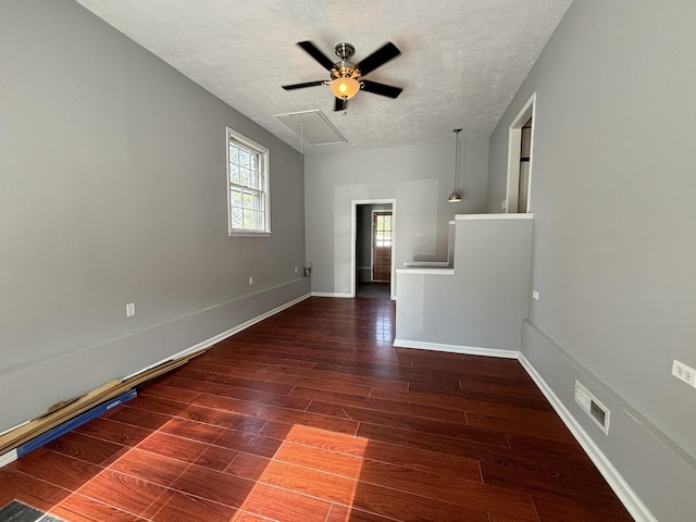 spare room with a textured ceiling, ceiling fan, and dark hardwood / wood-style floors