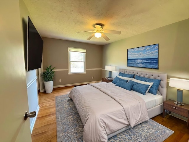 bedroom with ceiling fan, a textured ceiling, and hardwood / wood-style flooring