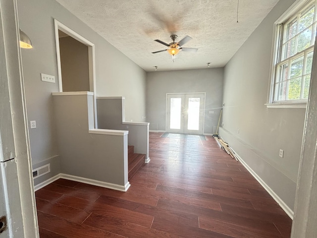 unfurnished room featuring dark hardwood / wood-style floors, ceiling fan, a textured ceiling, and french doors