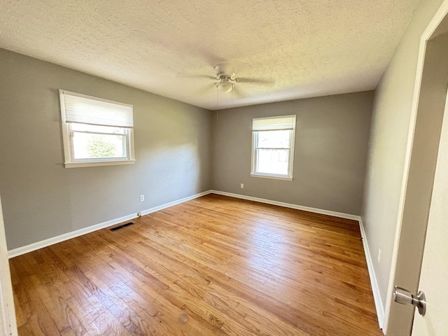 unfurnished room featuring ceiling fan, light wood-type flooring, and a textured ceiling