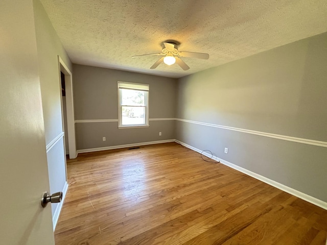 spare room with a textured ceiling, light wood-type flooring, and ceiling fan