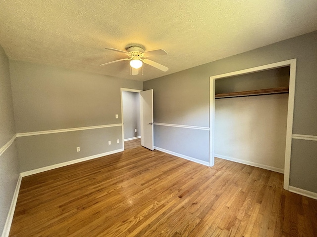 unfurnished bedroom with ceiling fan, a closet, a textured ceiling, and light hardwood / wood-style flooring