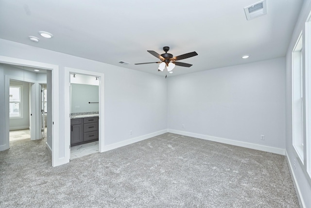 unfurnished bedroom featuring ceiling fan, light carpet, and connected bathroom