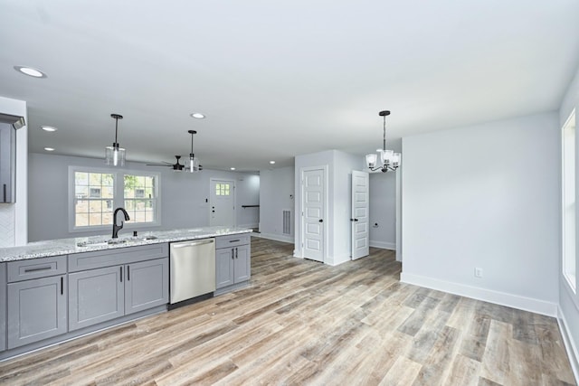 kitchen featuring gray cabinetry, ceiling fan with notable chandelier, sink, stainless steel dishwasher, and light stone counters