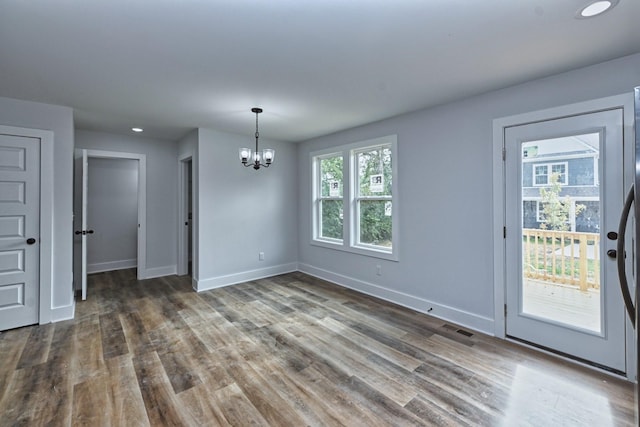 unfurnished dining area with dark hardwood / wood-style flooring and a notable chandelier