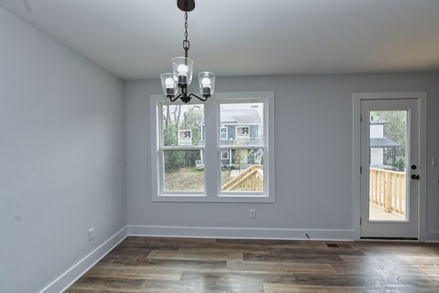 unfurnished dining area featuring dark hardwood / wood-style floors and an inviting chandelier