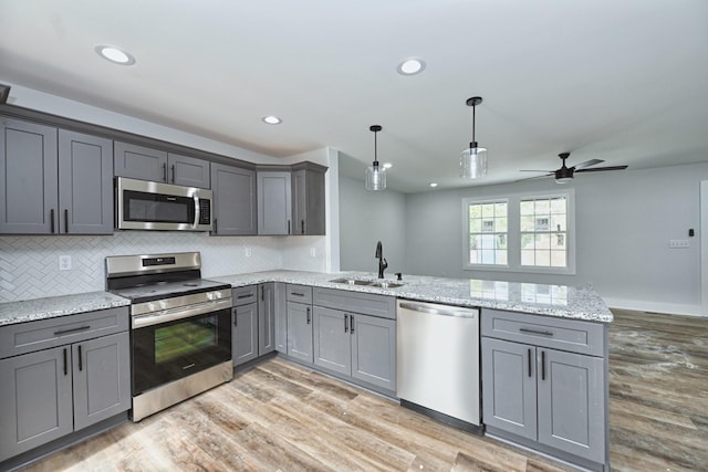 kitchen with hanging light fixtures, gray cabinets, sink, and appliances with stainless steel finishes