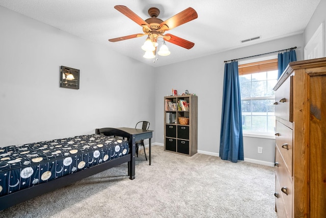 bedroom featuring a textured ceiling, light colored carpet, and ceiling fan