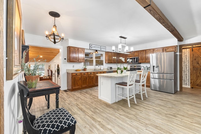 kitchen with stainless steel appliances, a kitchen island, hanging light fixtures, and a notable chandelier