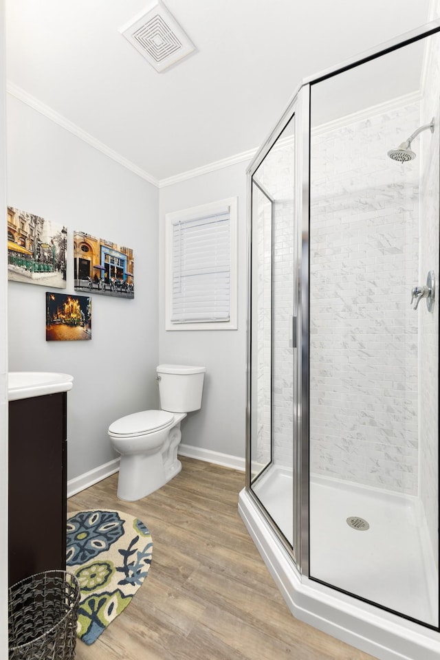 bathroom featuring ornamental molding, vanity, wood-type flooring, toilet, and a shower with shower door