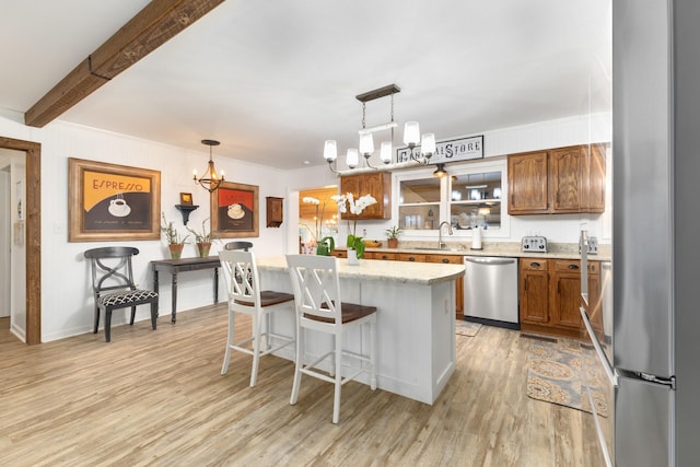 kitchen featuring a kitchen bar, stainless steel appliances, a kitchen island, and hanging light fixtures