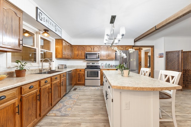 kitchen with a kitchen breakfast bar, sink, stainless steel appliances, and light hardwood / wood-style flooring