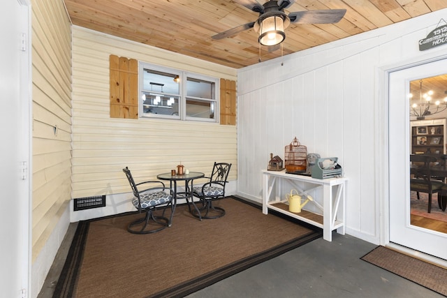 dining room featuring wood walls and ceiling fan with notable chandelier