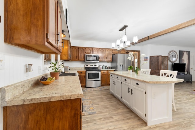 kitchen featuring a kitchen bar, light wood-type flooring, stainless steel appliances, a kitchen island, and white cabinetry