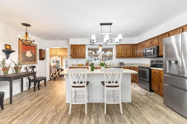 kitchen with pendant lighting, a center island, ornamental molding, appliances with stainless steel finishes, and a notable chandelier