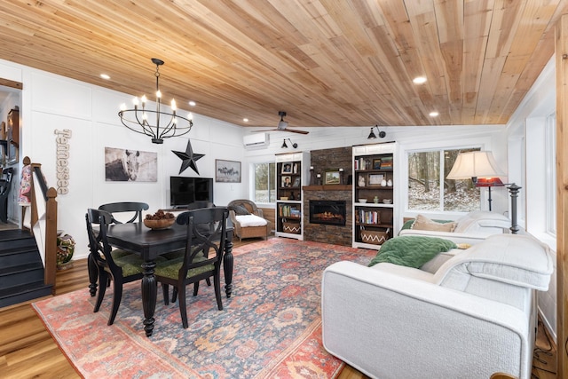 dining room with ceiling fan with notable chandelier, vaulted ceiling, wood-type flooring, built in features, and a fireplace