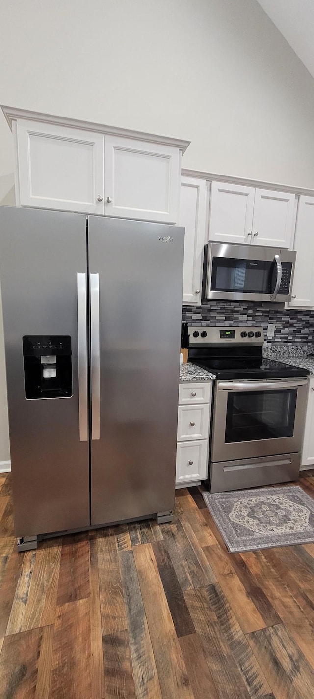 kitchen with appliances with stainless steel finishes, tasteful backsplash, light stone counters, dark wood-type flooring, and white cabinetry