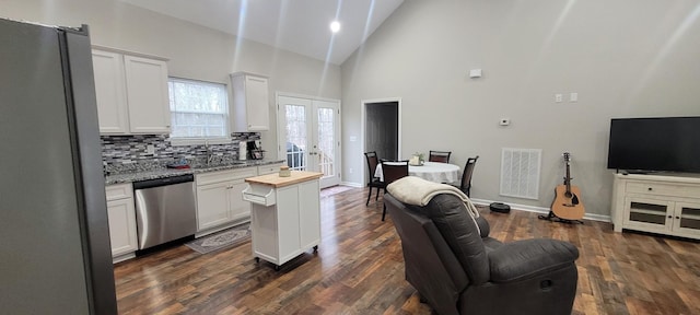 kitchen featuring appliances with stainless steel finishes, backsplash, french doors, high vaulted ceiling, and white cabinetry