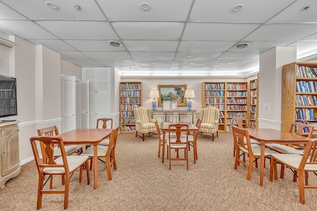 carpeted dining area featuring a drop ceiling