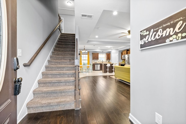 staircase with hardwood / wood-style floors, ceiling fan, and crown molding