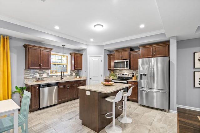 kitchen featuring tasteful backsplash, stainless steel appliances, sink, decorative light fixtures, and a center island