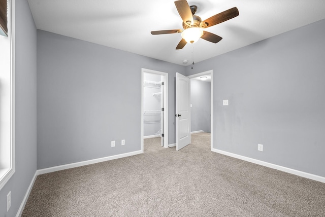 unfurnished bedroom featuring ceiling fan, a closet, light colored carpet, and a spacious closet