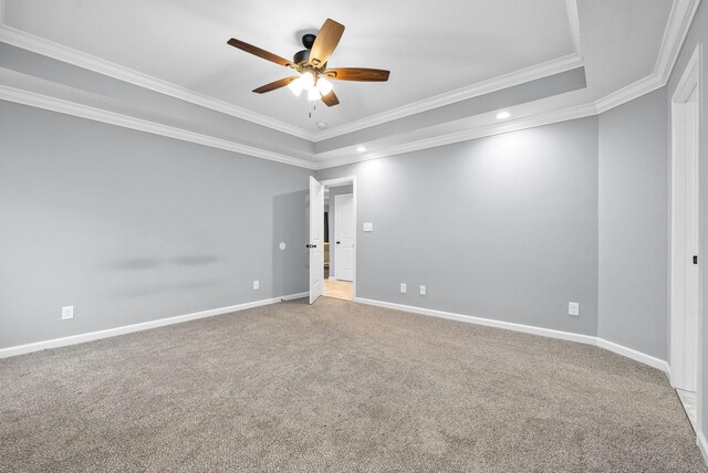 carpeted empty room featuring ceiling fan, ornamental molding, and a tray ceiling