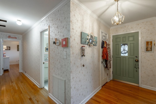 entrance foyer featuring hardwood / wood-style floors, ornamental molding, and a notable chandelier