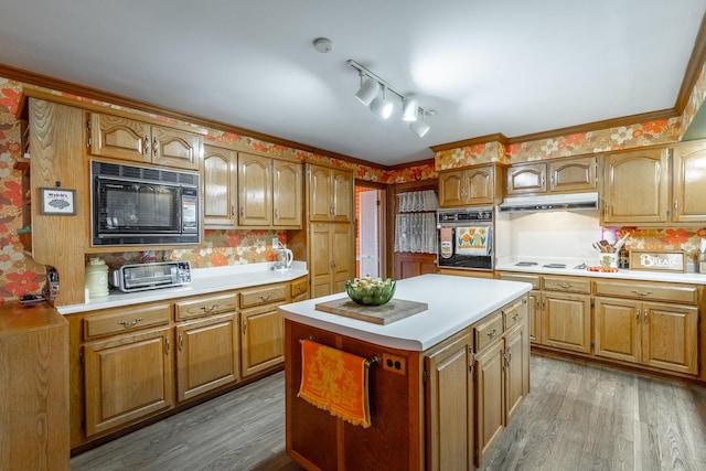 kitchen featuring light wood-type flooring, a center island, crown molding, and black appliances