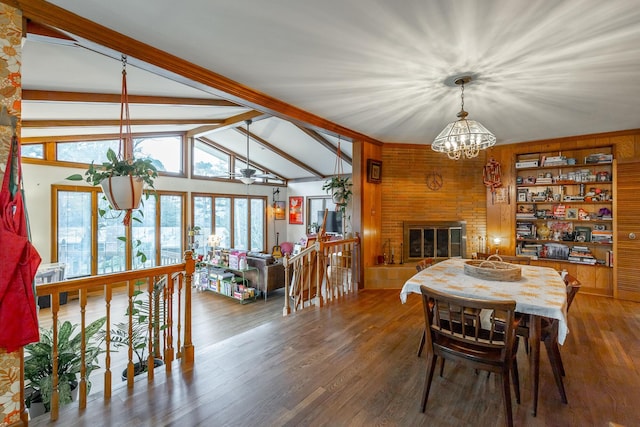 dining room featuring a large fireplace, an inviting chandelier, dark hardwood / wood-style flooring, built in features, and lofted ceiling with beams