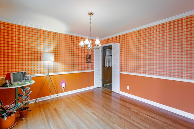 unfurnished dining area featuring wood-type flooring, ornamental molding, and a chandelier