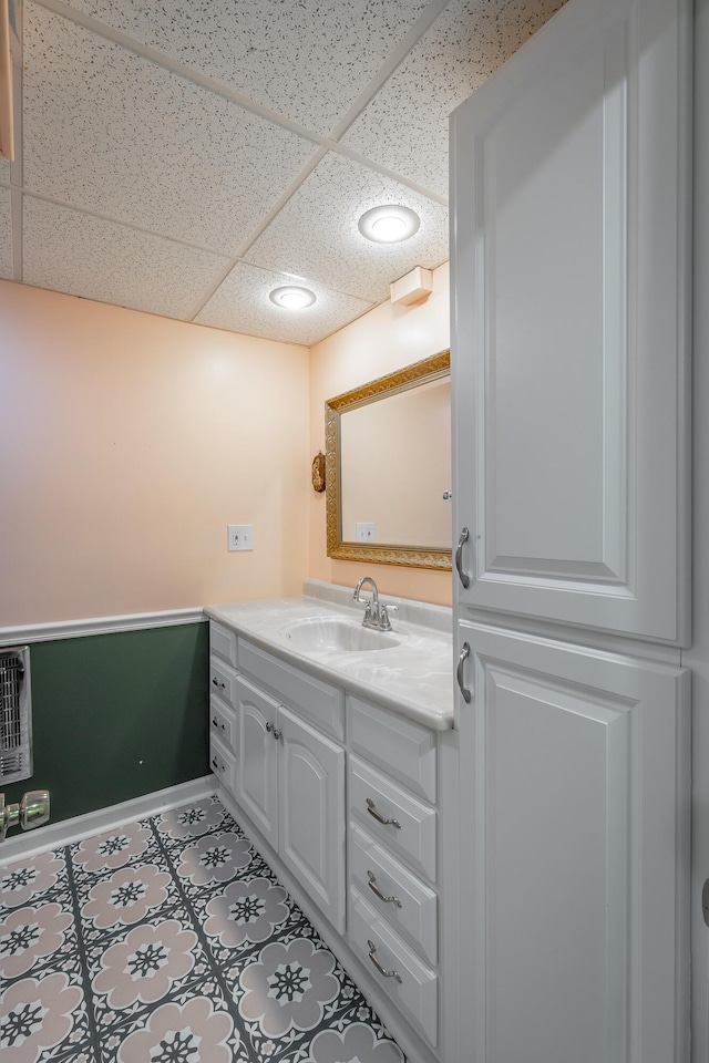 bathroom featuring a paneled ceiling, vanity, heating unit, and tile patterned flooring