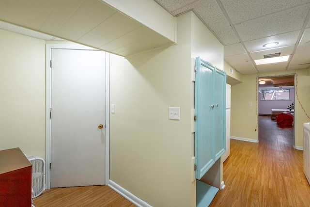 hall with a paneled ceiling and light hardwood / wood-style flooring