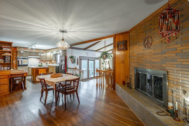 dining room featuring a tile fireplace, lofted ceiling, and hardwood / wood-style flooring