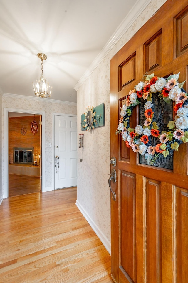 foyer entrance featuring a notable chandelier, light hardwood / wood-style floors, and crown molding