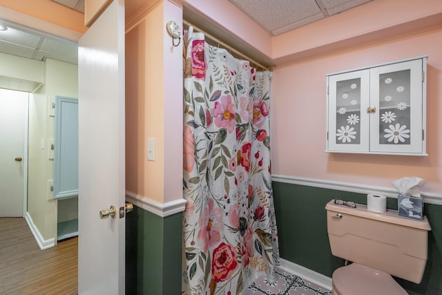 bathroom featuring a drop ceiling, toilet, and wood-type flooring