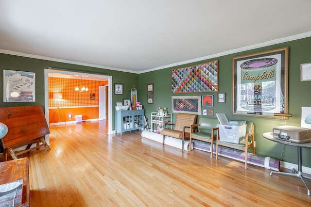 sitting room featuring a chandelier, ornamental molding, and light hardwood / wood-style flooring