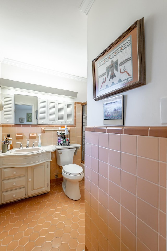 bathroom with tile patterned flooring, toilet, vanity, tile walls, and ornamental molding