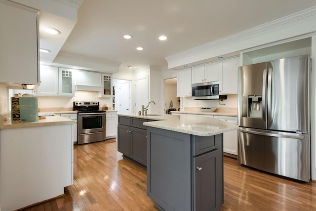 kitchen featuring light stone countertops, stainless steel appliances, an island with sink, gray cabinets, and white cabinets