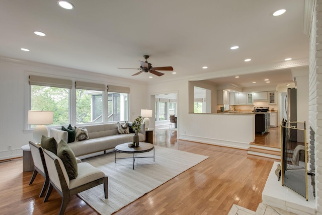 living room with light wood-type flooring, ceiling fan, and crown molding