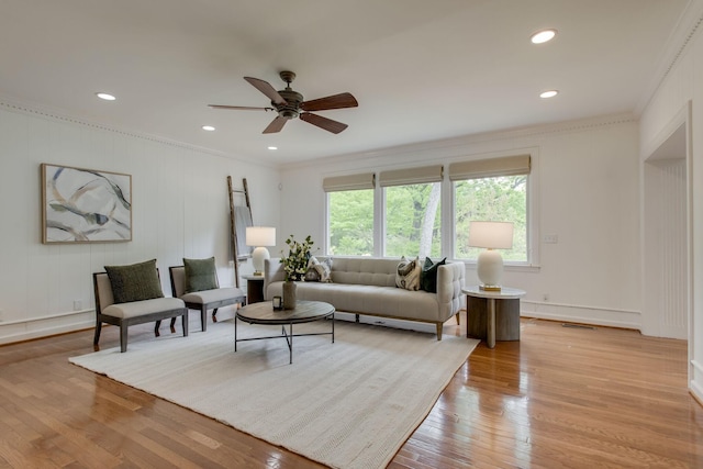 living room with light wood-type flooring, ceiling fan, and crown molding