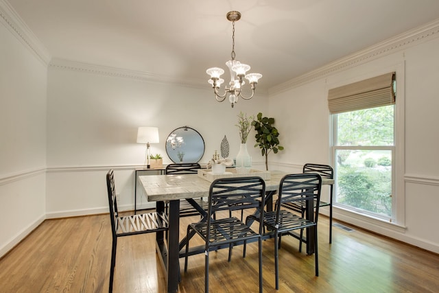 dining area featuring crown molding, hardwood / wood-style floors, and a chandelier