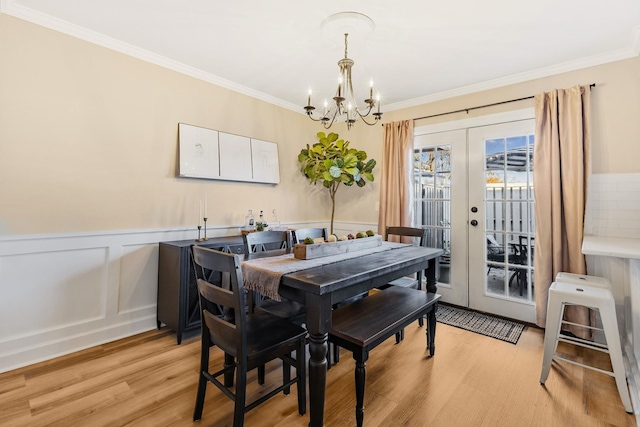 dining room with a chandelier, french doors, light wood-type flooring, and crown molding