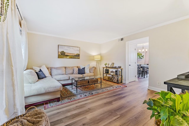 living room featuring a chandelier, hardwood / wood-style flooring, and ornamental molding