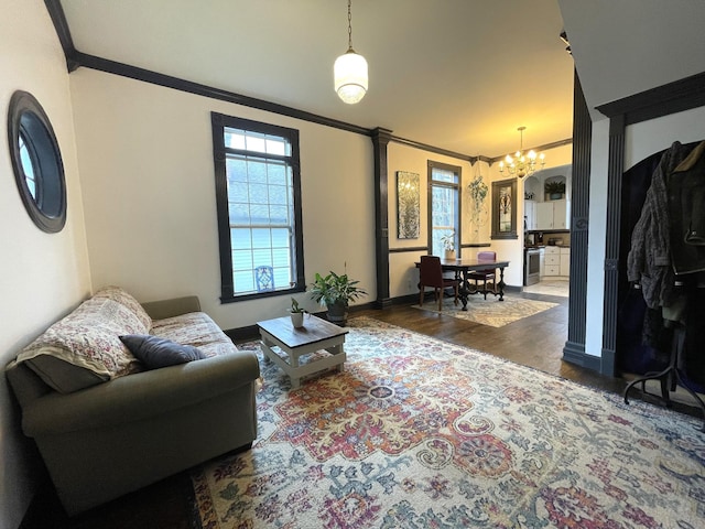 living room featuring crown molding, dark hardwood / wood-style floors, and a notable chandelier