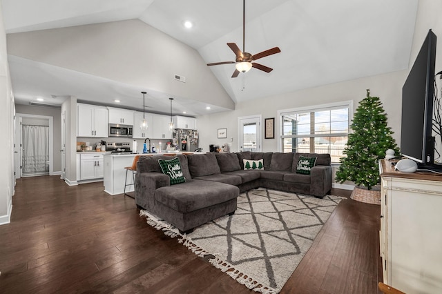 living room featuring dark hardwood / wood-style floors, ceiling fan, sink, and high vaulted ceiling