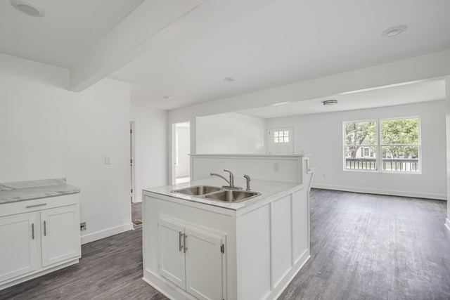 kitchen featuring a kitchen island with sink, sink, beam ceiling, dark hardwood / wood-style floors, and white cabinetry